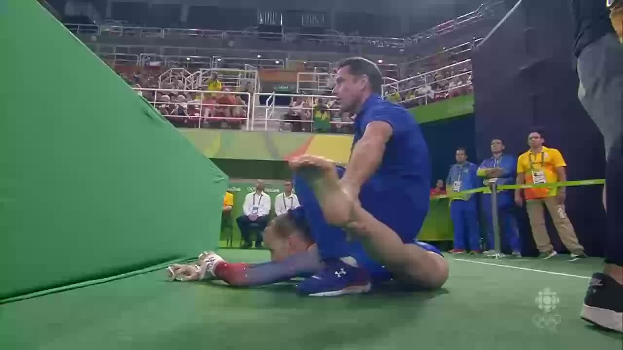 Gymnast Madison Kocian legs stretched by her trainer